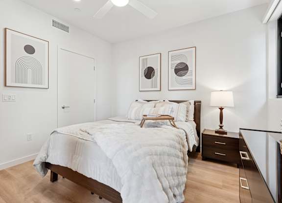 OnyxOnPark_SanDiego_CA_Model_1BR_ A bedroom with a large bed and two framed pictures on the wall.