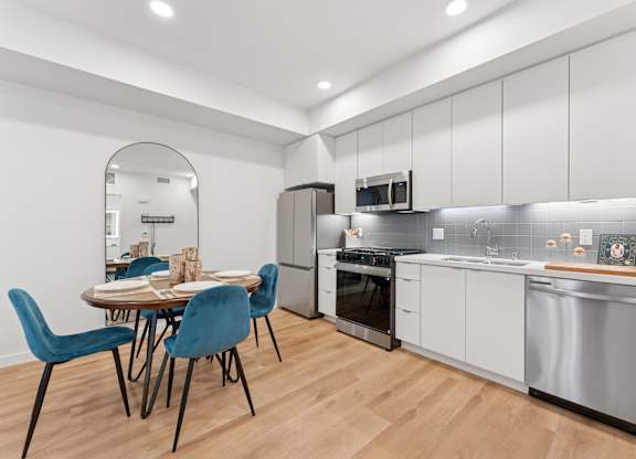 OnyxOnPark_SanDiego_CA_Model_1BR_ A modern kitchen with a dining table and chairs.
