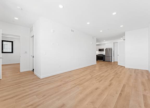 OnyxOnPark_SanDiego_CA_Vacant_2BR_ A large empty room with wooden floors and white walls.