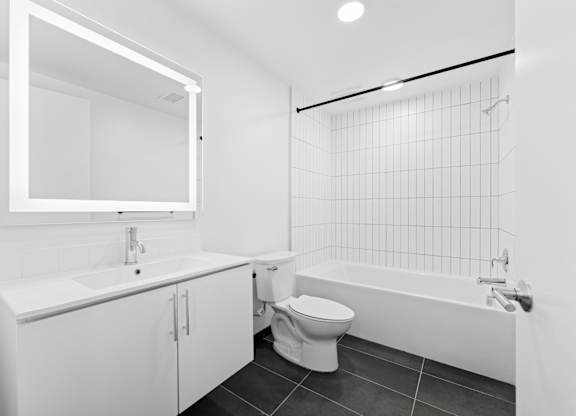 OnyxOnPark_SanDiego_CA_Vacant_2BR_ A white bathroom with a toilet, sink, and bathtub.