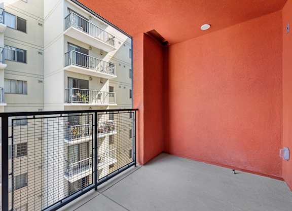OnyxOnPark_SanDiego_CA_Vacant_2BR_ A balcony with a black railing and a red wall.