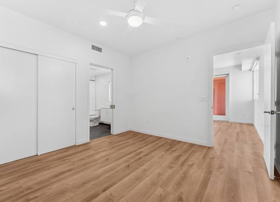 OnyxOnPark_SanDiego_CA_Vacant_2BR_B1_A room with white walls and wooden flooring with a ceiling fan.