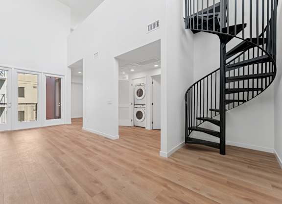 OnyxOnPark_SanDiego_CA_Vacant_Penthouse_A_A black spiral staircase in a white room with wooden flooring.