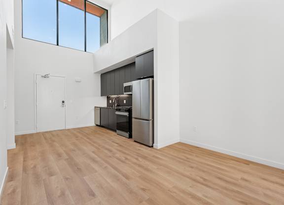 OnyxOnPark_SanDiego_CA_Vacant_Penthouse_A_OnyxOnPark_SanDiego_CA_Vacant_Penthouse_A_A kitchen with a refrigerator, oven, and sink is in a room with wooden floors and white walls.
