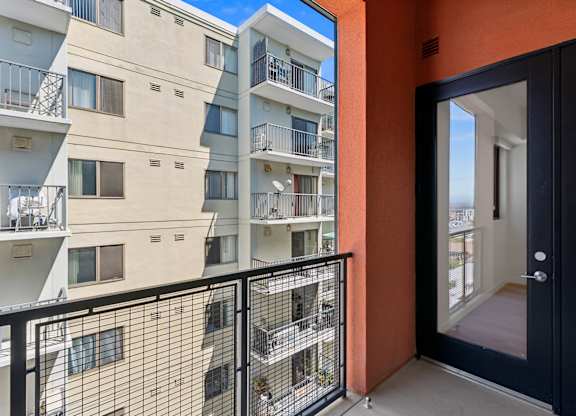 OnyxOnPark_SanDiego_CA_Vacant_Penthouse_A_A balcony with a black railing and a view of a building with orange and beige walls.