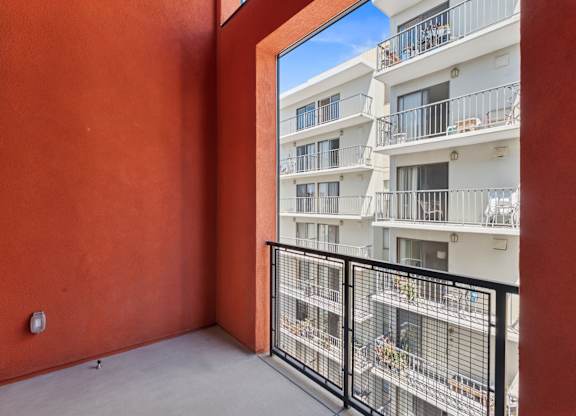 OnyxOnPark_SanDiego_CA_Vacant_Penthouse_A_A balcony with a black railing and a red wall.