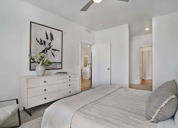 Alvera at the Meadows bedroom with a large bed, a dresser with a vase of flowers, and a framed picture on the wall.