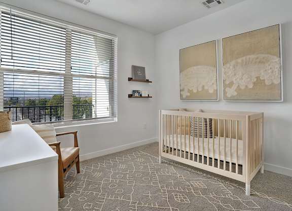 Alvera at the Meadows baby's room with a crib and a painting of a dinosaur on the wall.