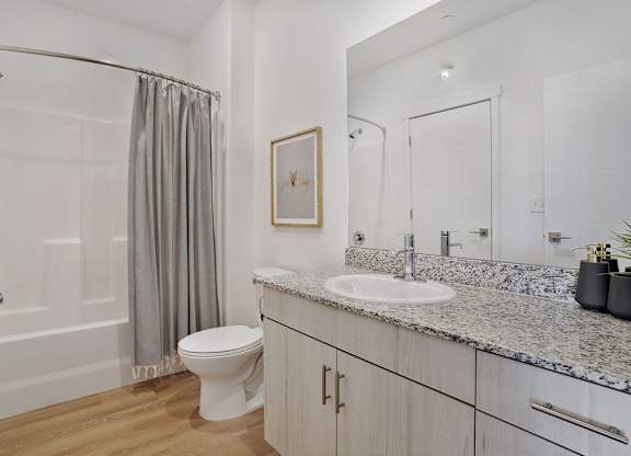 Alvera at the Meadows  bathroom with a white toilet, sink, and shower.