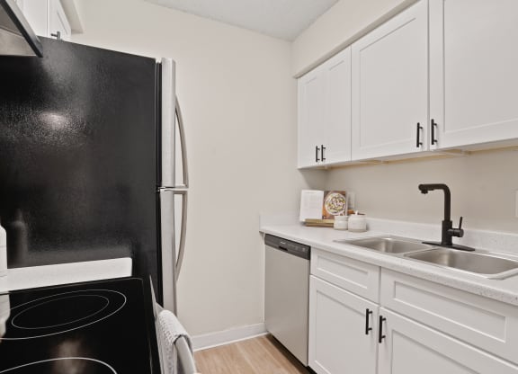 a kitchen with white cabinets and a black refrigerator and sink