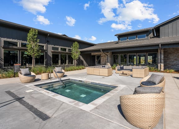 a patio with a pool and chairs in front of a building