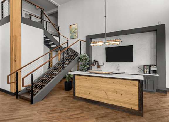 A modern kitchen with a wooden counter and a staircase.