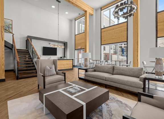 A modern living room with a staircase and a kitchen area in the background.
