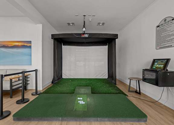 A room with a green carpet and a white wall with a painting on it.
