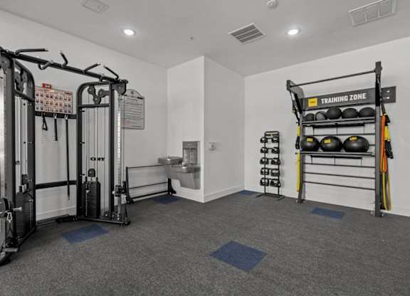 A gym with a weightlifting area and a rack of kettlebells.