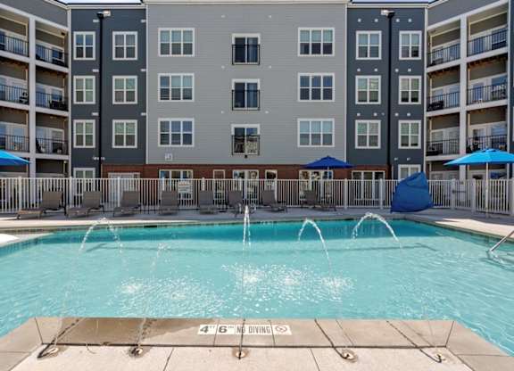 A large swimming pool in front of apartment buildings with a 4'6