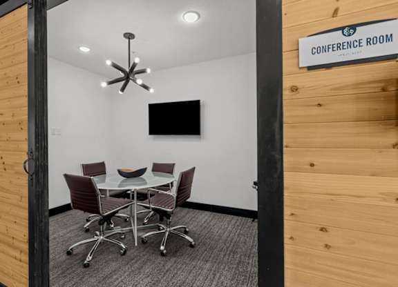 A conference room with a table and chairs and a sign on the wall.