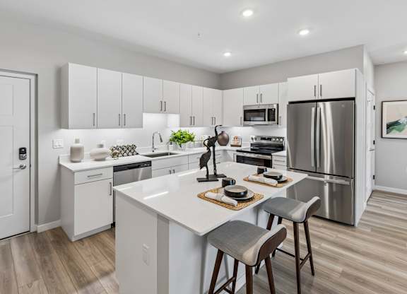 A modern kitchen with a white island and stainless steel appliances.