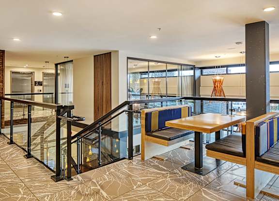 a seating area with tables and chairs in a lobby with a staircase