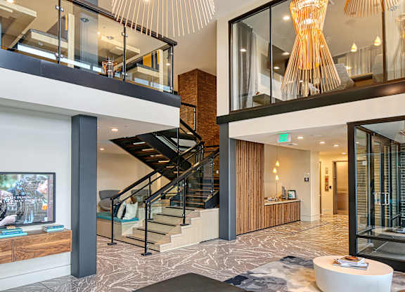 the lobby of a condo with a staircase and a tv