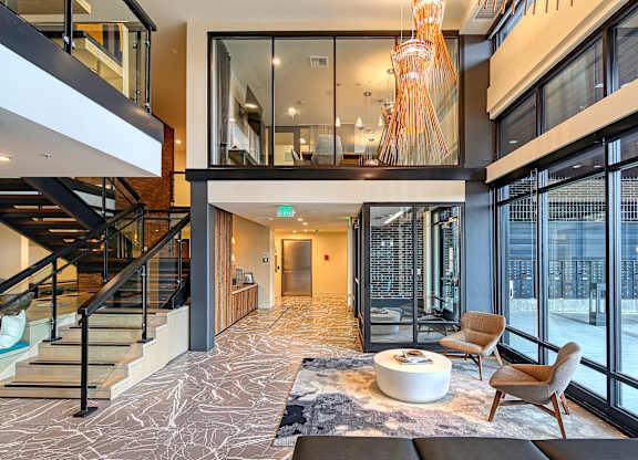 a living room with glass doors and a staircase and a table and chairs