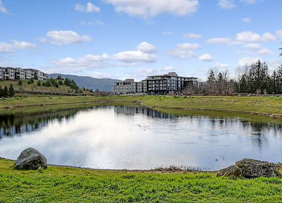 a pond with buildings in the background and a blue sky with clouds
