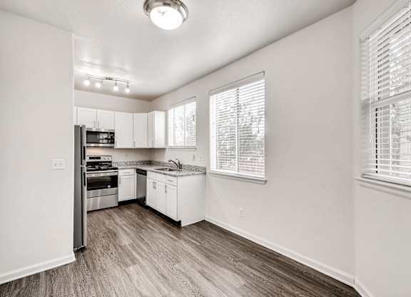 A kitchen with white cabinets and a wooden floor.