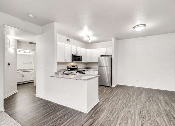 A kitchen with a refrigerator, microwave, and oven.