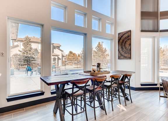 A dining room with a table and chairs in front of large windows.