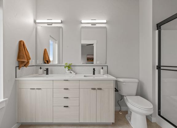 A white bathroom with a toilet, sink, and mirror.
