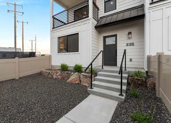 A modern house with a black front door and a gravel driveway.