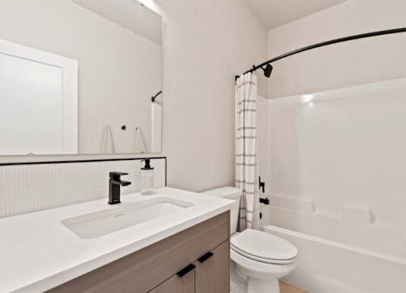 A white bathroom with a toilet, sink, and bathtub.