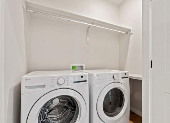 Two white washing machines in a small laundry room.