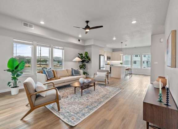 A living room with a sofa, a chair, a table, and a ceiling fan.