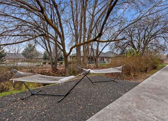 A hammock is strung between two trees in a park.