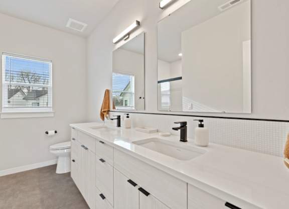 A bathroom with a white sink, toilet, and mirror.