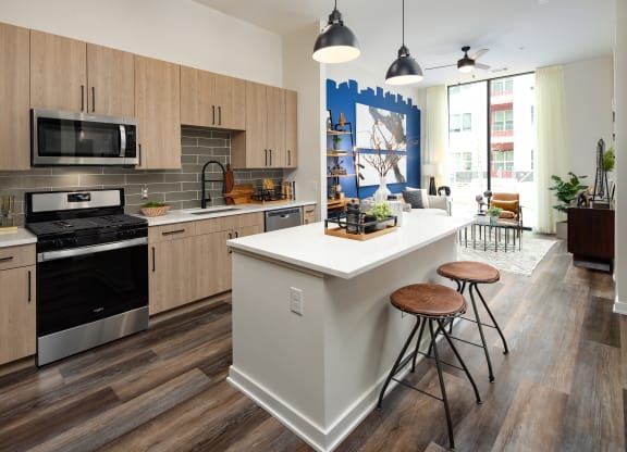a kitchen with a large white island with three stools in front of it