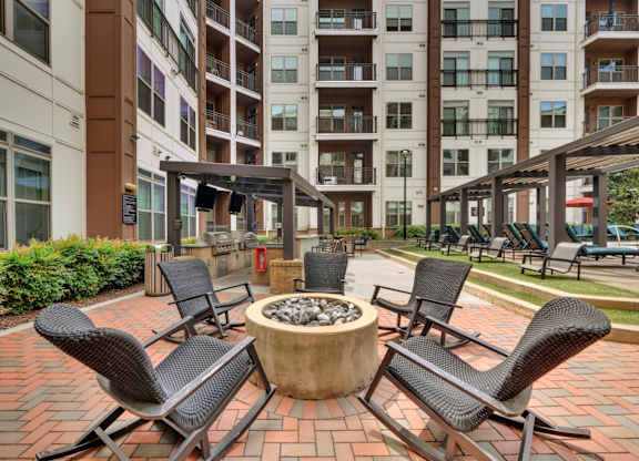 A patio with chairs and a fire pit in front of a building.
