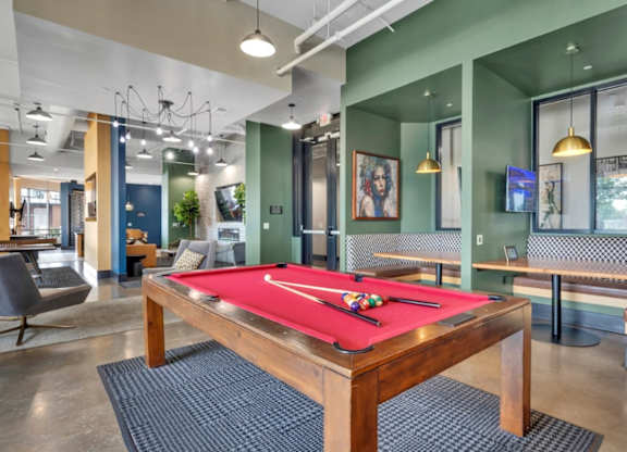 A pool table is in the middle of a room with a green wall.