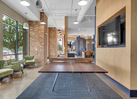 A room with a long table and chairs in front of a brick wall.