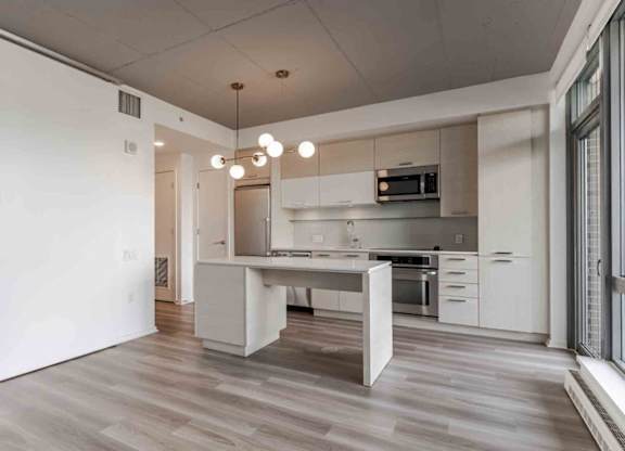 A modern kitchen with a white island and wooden floors.