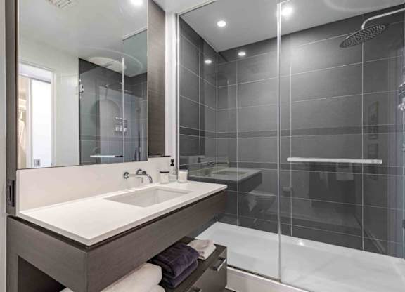 A modern bathroom with a white sink and a walk-in shower.