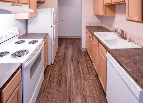 A kitchen with white appliances and wooden cabinets.