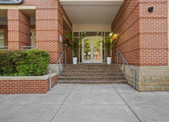 A red brick building with a glass door and steps leading up to it.