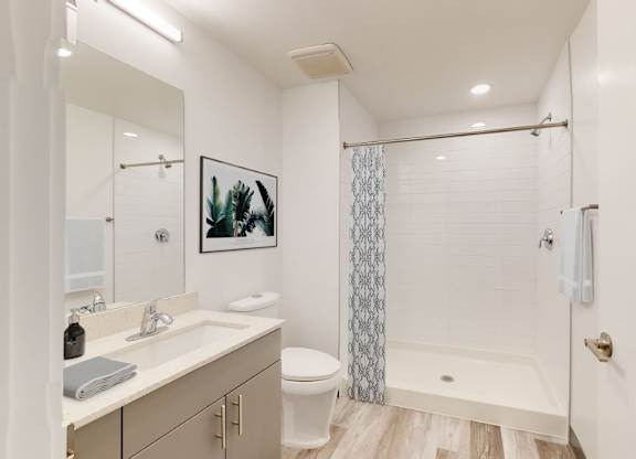 A white bathroom with a toilet, sink, and shower.