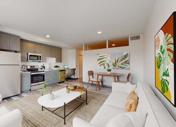 A modern kitchen with white appliances and a dining area with a white couch and a painting on the wall.