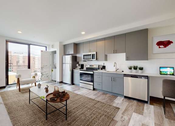 A modern kitchen and living room with a large window and a view of the city.