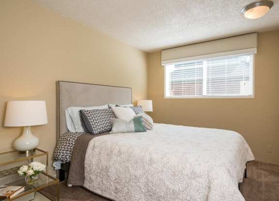 A bedroom with a bed, nightstand, and window.