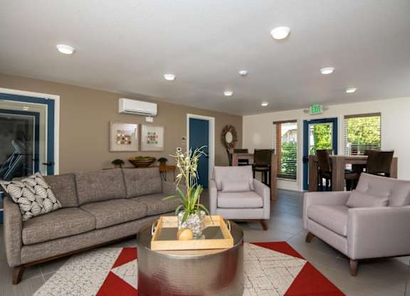 A living room with a grey couch, a coffee table, and a wreath on the wall.