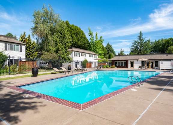 A swimming pool surrounded by a concrete patio and a fence.